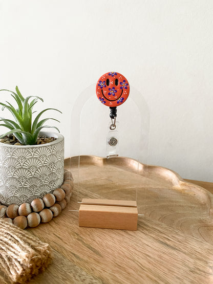 Hand painted orange floral smiley face polymer clay badge reel